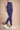 Woman wearing a purple sports bra and leggings on a beige background