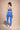 Woman wearing a blue sports bra and leggings set on a beige background