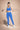 Woman in blue athletic wear holding resistance bands against a beige background