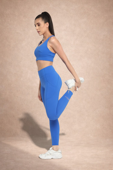 Woman in blue athletic wear stretching on a beige background