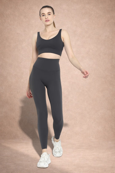 Woman wearing a gray athletic outfit on a beige background