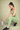 Woman in green athletic wear holding a water bottle on a beige background