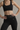 Person wearing a black sports bra and black lace leggings against a neutral background