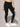 Person wearing a black sports bra and black lace leggings against a neutral background