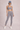 Person wearing a gray sports bra and gray lace leggings against a neutral background