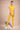 Woman wearing a yellow athletic outfit on a beige background