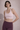 Woman wearing a light pink sports bra and maroon leggings against a neutral background