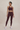Woman wearing a maroon athletic outfit on a beige background