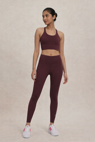 Woman wearing a maroon athletic outfit on a beige background