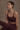 Woman wearing a maroon athletic outfit on a beige background