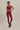 Woman wearing a red sports bra and leggings on a beige background