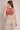 Woman wearing a brown sports bra and beige leggings against a beige background