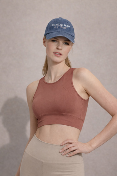 A woman wearing a sports bra in a solid color with mesh fabric panels on the back, paired with high-waisted leggings.