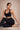 Woman in black sports bra and leggings sitting on a beige background