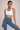Woman wearing a white sports bra and blue leggings on a beige background