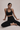 Woman in black athletic wear sitting on a light gray background