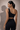 Woman wearing a black scalloped-edge top against a neutral background