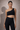 Woman wearing a Shakti Warrior black scalloped one-shoulder top and pants