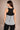 Woman wearing a black and gray tank top with a visible brand logo on a beige background