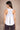 Woman wearing a white tank top with a cutout design on a beige background