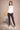 Woman holding a basketball wearing a white sleeveless top and dark leggings on a beige background