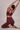 Person wearing a burgundy sports bra and leggings set, stretching against a neutral background