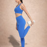 Woman in blue athletic wear stretching on a beige background