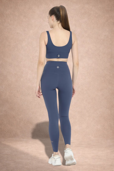 Woman wearing a blue athletic outfit standing against a beige background