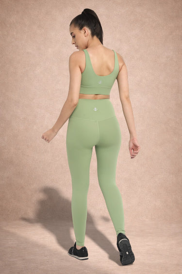 Woman wearing a green athletic outfit on a beige background