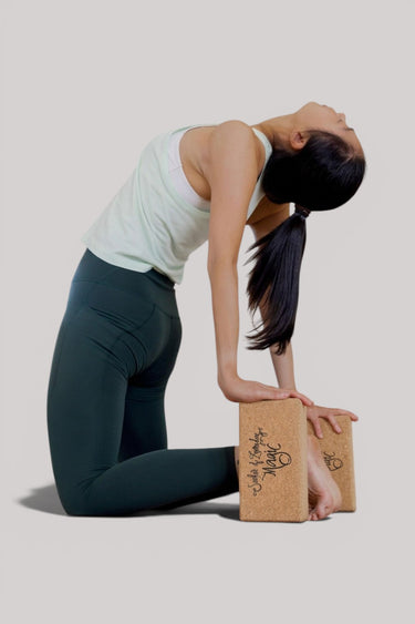 Woman practicing yoga with a cork block on a plain background