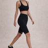 Woman wearing a Shakti Warrior black athletic outfit with shoes on a neutral background