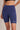 Blue athletic shorts with a Shakti Warrior brand logo on a neutral background