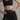 Person wearing a black sports bra and black lace leggings against a neutral background