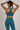 Woman in a teal sports bra and matching teal leggings