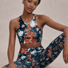 Woman wearing a floral sports bra and leggings set on a beige background