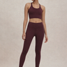 Woman wearing a maroon athletic outfit on a beige background
