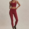 Woman wearing a red sports bra and leggings on a beige background