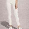 Person wearing white leggings and white sneakers on a light pink background