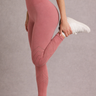 Person wearing pink leggings and white sneakers on a plain background