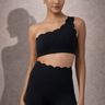 Woman wearing a Shakti Warrior black scalloped one-shoulder top and pants