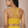 Woman wearing a yellow sports bra and leggings. The bra has a criss cross pattern giving high support